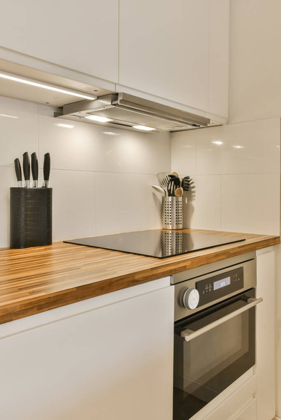 кухня з білими шафами і дерев'яними стільницями в центрі зображення є духовка, посудомийна машина, і - Фото, зображення