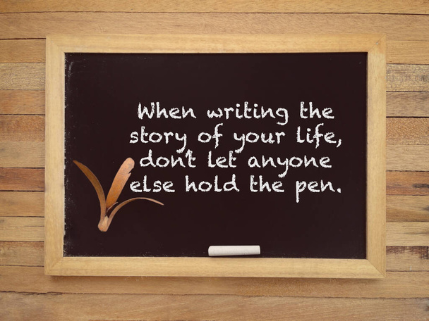 Мотивационная и вдохновляющая формулировка. Когда пишешь "Историю своей жизни", не позволяй никому другому держать ручку, написанную на доске. С размытым стилизованным фоном. - Фото, изображение