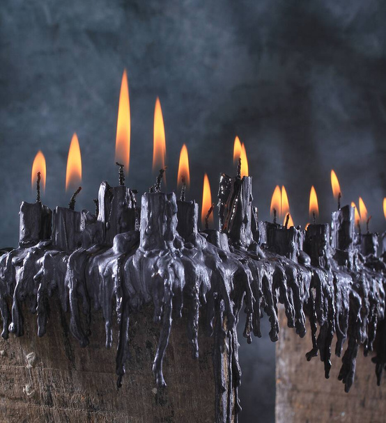 Stillleben-Fotografie, schwarze Kerze auf einem Holztisch vor dunklem Hintergrund - Foto, Bild