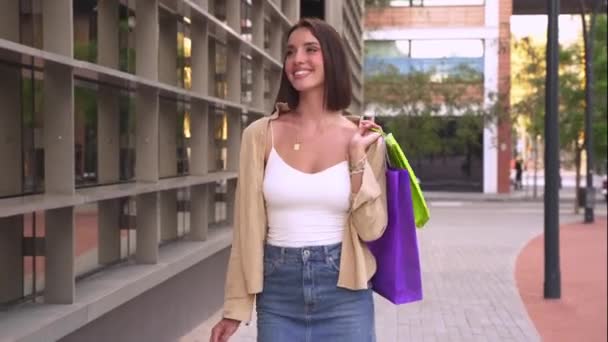Счастливая белая женщина с сумками для покупок ходит по солнечной улице. Концепция образа жизни, покупки, продажи, потребления. - Кадры, видео