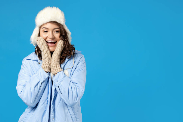 Das Mädchen in warmer Winterkleidung, auf blauem Hintergrund. - Foto, Bild
