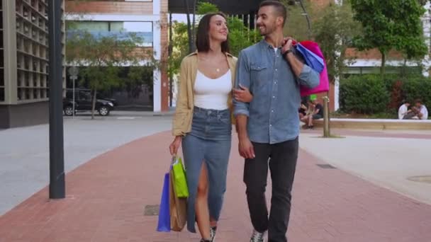 Een paar draagtassen die glimlachen op straat tijdens een verkoopweek. Begrip "consument" - Video