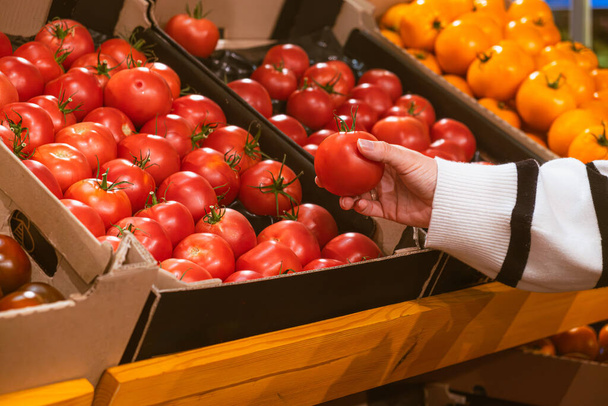 hand nemen tomaten uit supermarkt plank kopieerruimte - Foto, afbeelding