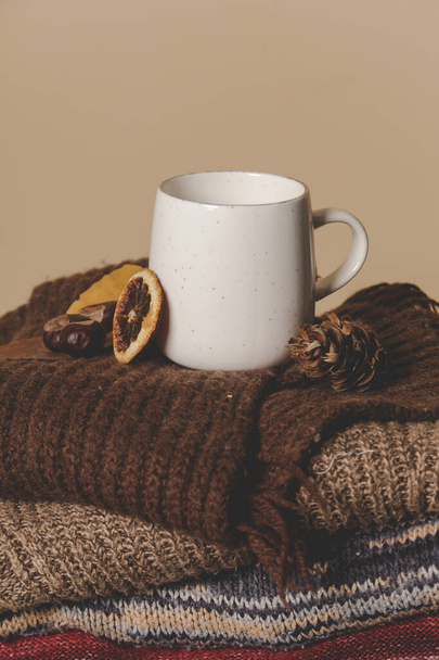 Cozy winter lifestyle concept. Cup of hot drink with warm knitted clothes. - Photo, Image