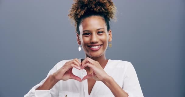 Happy woman, heart hands and love for care, support or compassion isolated against a studio background. Portrait of female person smile showing shape, emoji or icon for romantic gesture on mockup. - Footage, Video