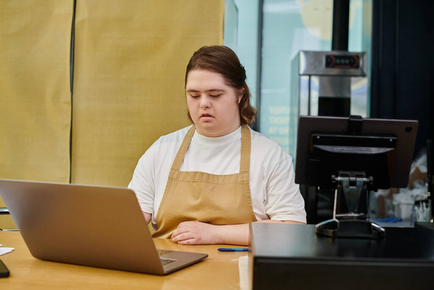 jonge vrouwelijke werknemer met psychische stoornis werken op laptop in de buurt van cash terminal op de toonbank in cafe - Foto, afbeelding