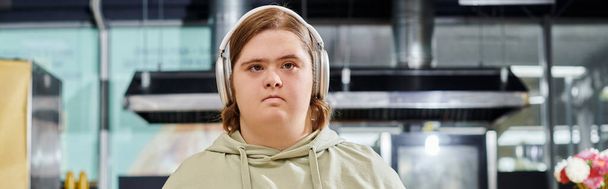 cliente joven con discapacidad mental escuchando música en auriculares inalámbricos en la cafetería, pancarta - Foto, Imagen
