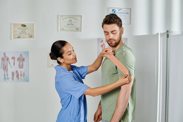 atrakcyjny młody lekarz konsultujący się z jej przystojnym pacjentem na temat taśm kinezjologicznych, opieki zdrowotnej - Zdjęcie, obraz
