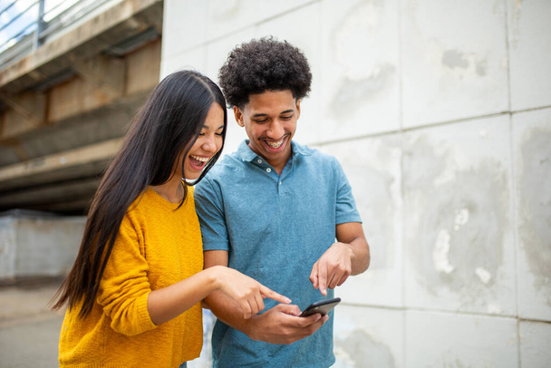 Portrait jeune couple heureux pointant vers les téléphones mobiles - Photo, image