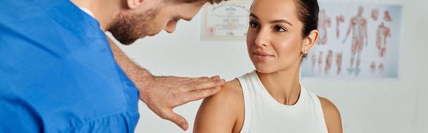 atrakcyjna kobieta patrząc na jej brodatego lekarza podczas gdy on sprawdza jej ramię, opiekę zdrowotną, baner - Zdjęcie, obraz