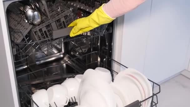 Close up view of female hand filling, inserting, loading dirty dishes, placing white plates into an open automatic built-in dishwasher. Housewife does her housework. - Footage, Video