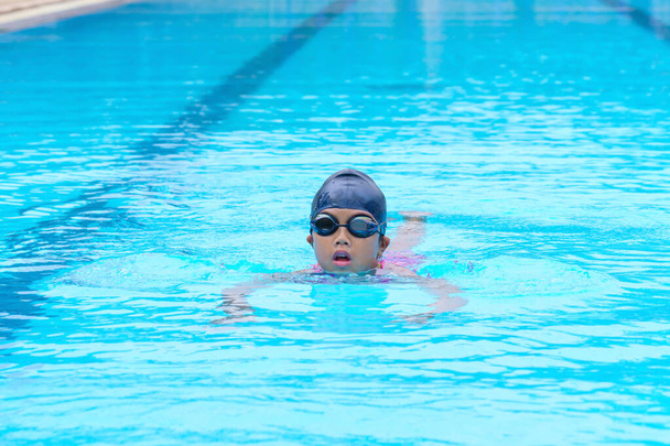 child swimmer swim in swimming pool. Water sports training and competition, learning to swim classes for children. - Photo, Image