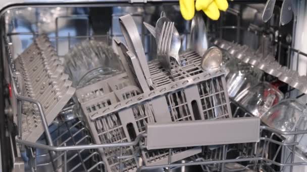 Крупним планом жіноча рука завантажує брудний посуд, розміщуючи білі тарілки у відкриту автоматичну вбудовану посудомийну машину з нержавіючої сталі на сучасній домашній кухні. прання - Кадри, відео
