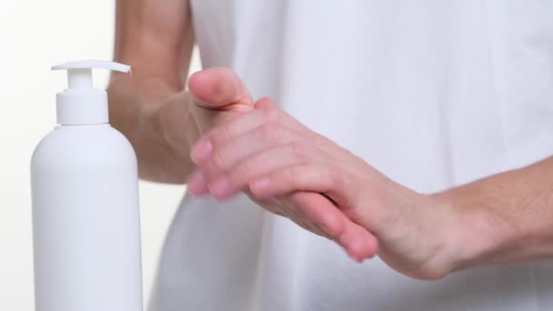 Against a pristine white background, the camera focuses on the hands of a man, meticulously applying hand cream. Each movement reflects precision and care, emphasizing the importance of hand skincare. - Footage, Video