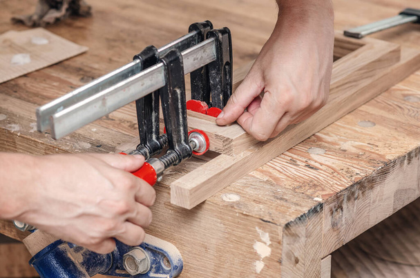 Las abrazaderas de carpintero se fijan a las tablas. Encolado de carpintería en el taller - Foto, Imagen