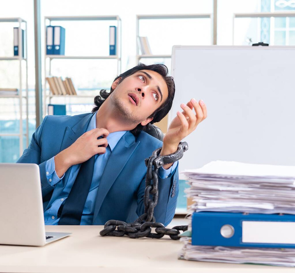 Angeketteter männlicher Angestellter unzufrieden mit exzessiver Arbeit - Foto, Bild