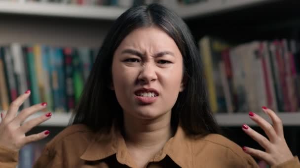 Vihainen raivoissaan stressaantunut aasialainen nainen huutaa ärtynyt tunne yliopiston kirjastossa korealainen tyttö naispuolinen opiskelija huutaa huutaa hullu hullu asiakas väittäen huutaa tuntea vihaa stressiä raivo aggressio - Materiaali, video