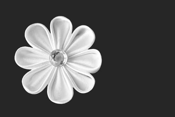 Flor de tela blanca hecha a mano (kanzashi) aislada sobre fondo gris oscuro con espacio para copiar - Foto, imagen