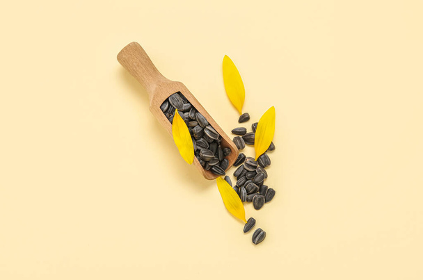 Ayçiçeği tohumlu ahşap kepçe ve sarı arka planda taç yaprakları - Fotoğraf, Görsel