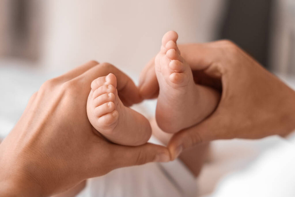 Mani di mamma con minuscole gambe di bambino sul letto a casa - Foto, immagini