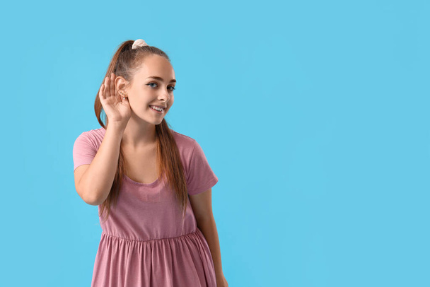 Teenage dívka se snaží slyšet něco na modrém pozadí - Fotografie, Obrázek