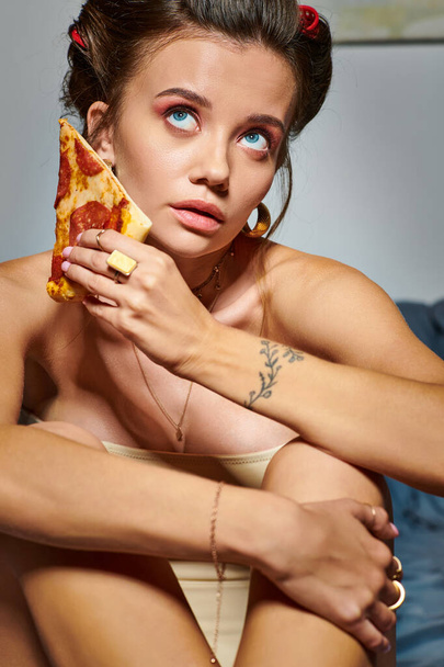 ελκυστική σέξι γυναίκα με μπούκλες μαλλιών σε δελεαστικό κορσέ ποζάρουν με φέτα νόστιμη πίτσα - Φωτογραφία, εικόνα