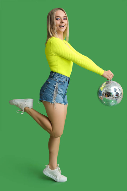 Kaunis nuori nainen disco pallo vihreällä taustalla - Valokuva, kuva