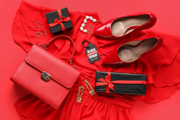 Composition avec des vêtements féminins élégants, accessoires, chaussures et cadeaux sur fond rouge. Vente Black Friday - Photo, image