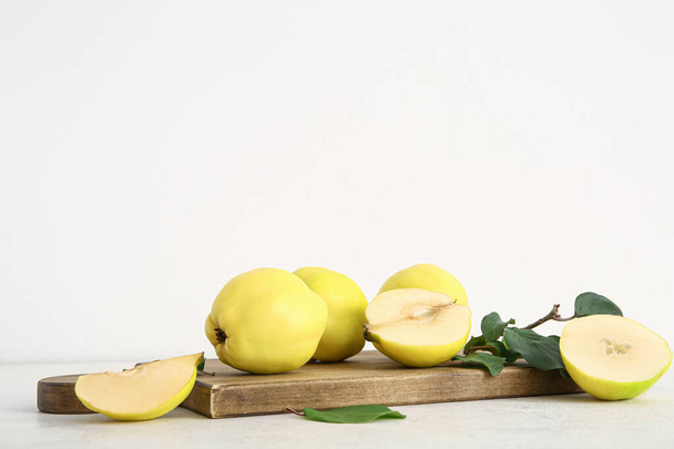Dřevěné desky se sladkými zralé quinces a listy na bílém pozadí - Fotografie, Obrázek