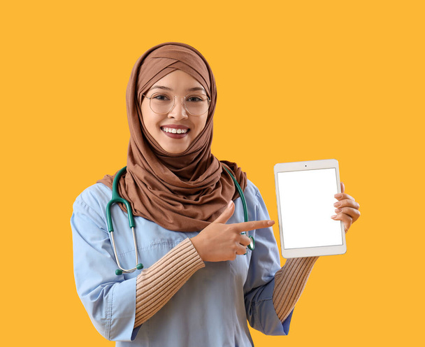Muslimi lääketieteellinen harjoittelija tabletti tietokone keltaisella pohjalla - Valokuva, kuva