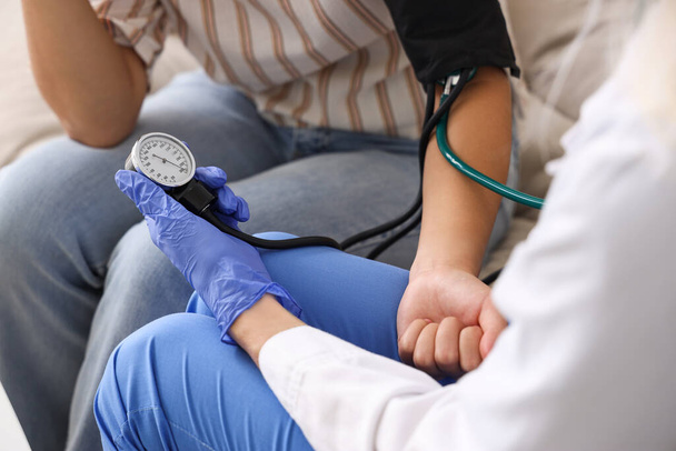 Жінка-лікар вимірює кров'яний тиск у пацієнта вдома, крупним планом - Фото, зображення