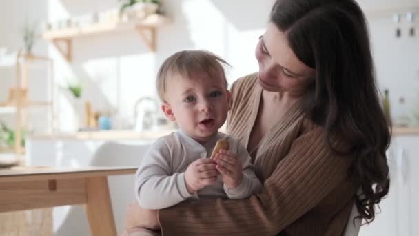 Mother tenderly embraces little son at kitchen. Arms wrap around him, creating a safe haven filled with unconditional love. Their connection is palpable, and the room seems to glow with tenderness. - Footage, Video