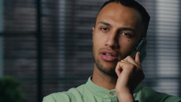 Close-up poważne sfrustrowany Afrykanin amerykański człowiek mówi przez telefon komórkowy martwi się zdezorientowany smutny etniczny facet mężczyzna przedsiębiorca kierownik biura odbieranie połączeń biznesowych za pomocą smartfona - Materiał filmowy, wideo