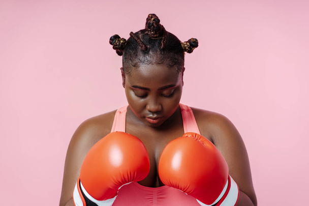 African american female boxer in red boxing gloves training isolated on pink background. Attractive woman doing sports, motivation, healthy lifestyle concept - Photo, Image
