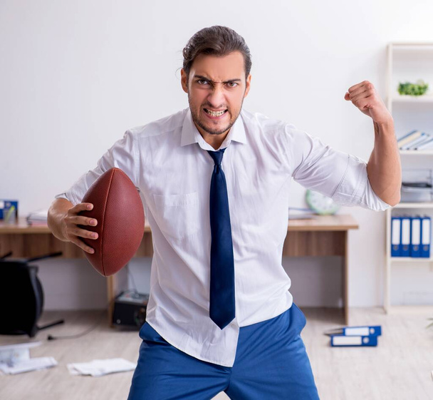 Un jeune employé lance une balle de rugby au bureau
 - Photo, image