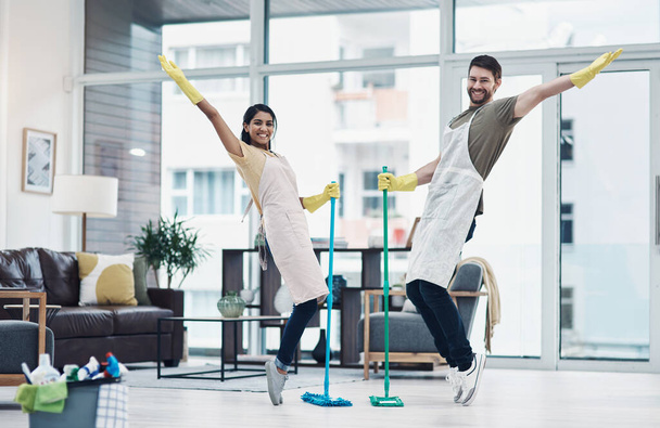 Putting a twist on those daily household tasks. a happy young couple having fun while mopping the floor at home - Photo, Image