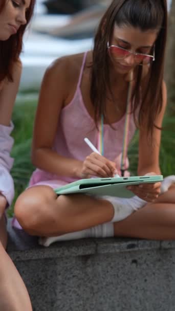 Zwei attraktive junge Mädchen nutzen Tablets, während sie online auf der Straße der Stadt arbeiten. Hochwertiges 4k Filmmaterial - Filmmaterial, Video