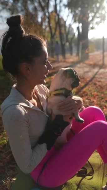 V podzimním parku je vidět šťastná mladá žena, jak objímá svého psího psa. Vysoce kvalitní 4K záběry - Záběry, video
