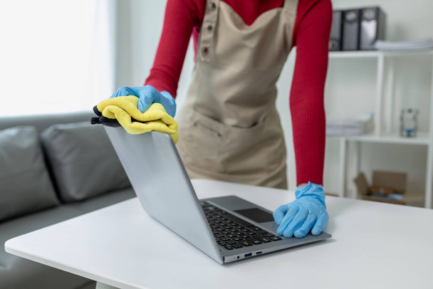 Janitor cleaning the office,  Clean the notebook with a rag, wear gloves and wipe with a towel, Wear rubber gloves when working with cleaning chemicals, cleaning idea. - Photo, Image