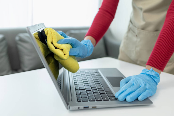 オフィスを掃除するジャニスターは,オフィスを掃除し,ラグでノートをきれいにし,手袋を着用し,タオルで拭きます,化学薬品を掃除するときのゴム製手袋,クリーニングのアイデア. - 写真・画像