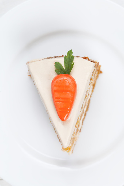 Pedaço de saboroso bolo de esponja de cenoura com creme de pastelaria e pequenas cenouras laranja em cima
 - Foto, Imagem