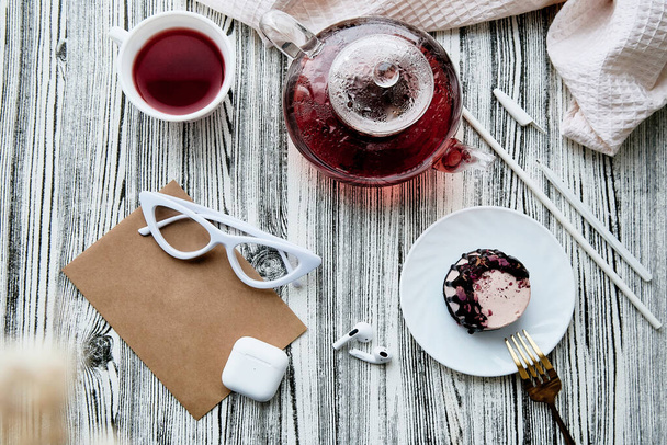 Kobiece śniadanie, różowy nerkowca bez cukru i bezglutenowe ciasto i naturalna herbata. Koperta makieta, słuchawki i płaskie układanie szkła - Zdjęcie, obraz