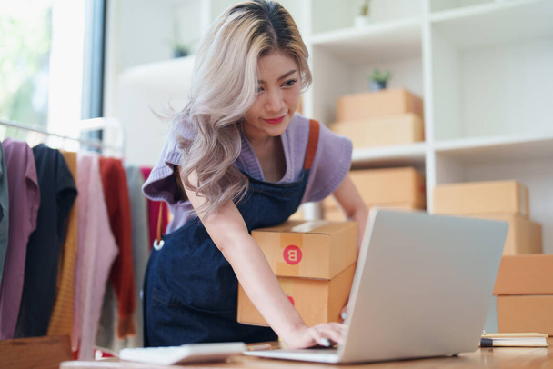 Aziatische vrouwelijke ondernemer behandelt levering van orders aan klanten. - Foto, afbeelding