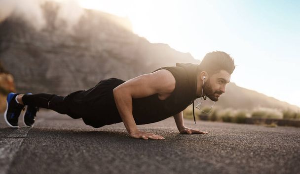 Ganas mucho más cuando no te rindes. un joven deportivo haciendo flexiones mientras hace ejercicio al aire libre - Foto, imagen