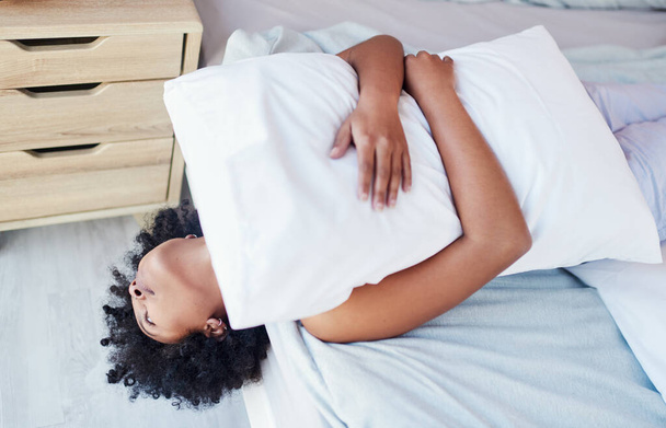 Estoy súper aburrido. una mujer abrazando su almohada mientras está acostada en su cama - Foto, Imagen