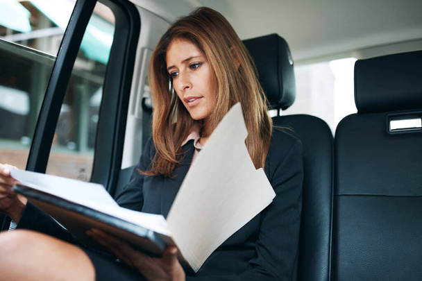 Делаю работу на ходу. зрелая деловая женщина, занимающаяся бумажной работой на заднем сиденье автомобиля - Фото, изображение
