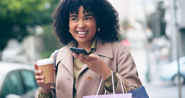 Boldog nő, kávé és telefon a kommunikációhoz odakint, város és utca ingázáshoz. Afrikai, üzletember és mosolyogni bevásárló táskák, miközben beszél a mobil alkalmazás, hálózat vagy internet. - Fotó, kép