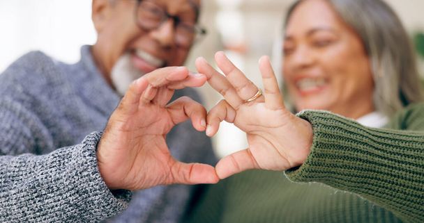 Smile, heart hands or old couple with support, love or hope in a marriage commitment at home together. Happy, valentines day blur or romantic senior man with trust or elderly woman on anniversary. - Photo, Image