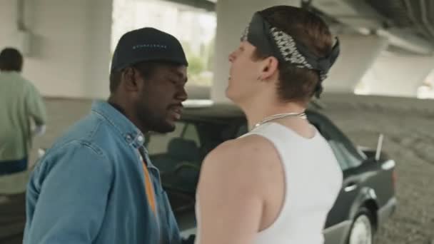 Afrikai-amerikai és kaukázusi fickó rapper ruhát visel, tologatja egymást, miközben egy híd alatt verekszik a bűnügyi körzetben. - Felvétel, videó