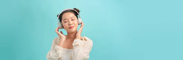 Gelukkig opgewonden meisje draagt een draadloze hoofdtelefoon, luistert naar muziek, voelt zich positief en ontspannen - Foto, afbeelding